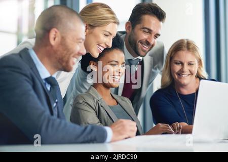 Travailler dur comme une équipe orientée objectifs. Groupe d'hommes d'affaires travaillant ensemble sur un ordinateur portable dans un bureau. Banque D'Images