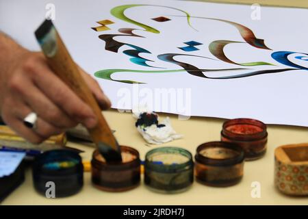 Un artiste de calligraphie et ses écrits arabes. Banque D'Images