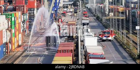 Mannheim, Allemagne. 24th août 2022. Les pompiers refroidissent un conteneur rempli de 200 barils d'hydrosulfite après un déversement de produits chimiques dans le port de Mühlauhafen. Du gaz liquéfié s'est échappé d'un conteneur maritime sur le site de l'usine mardi. Une réaction chimique s'est produite, produisant des irritants et des vapeurs toxiques. Depuis mardi après-midi, une opération à grande échelle est en cours, dans laquelle les pompiers de Mannheim sont soutenus par la police de l'eau, l'organisation de secours technique et d'autres. (Meilleure qualité possible) Credit: Dieter Leder/dpa/Alay Live News Banque D'Images