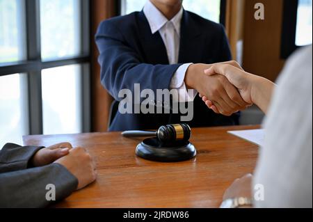 Un avocat professionnel de sexe masculin en costume formel se met entre les mains de son client après avoir conclu la transaction et avoir été embauché pour gérer son procès. Image rognée Banque D'Images