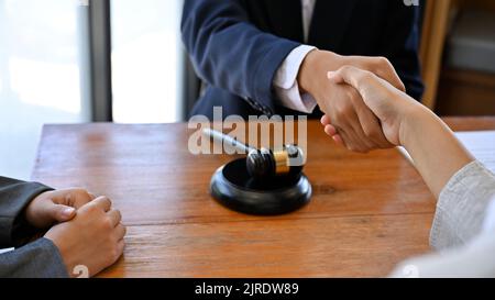 Une femme d'affaires se serre la main pour sceller un accord avec ses avocats ou avocats après avoir signé l'accord de poursuite. Image rognée Banque D'Images