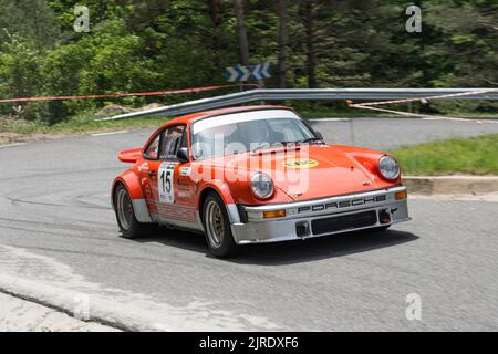 Une Porsche 911 rouge avec autocollants et réglage sur une route étroite Banque D'Images