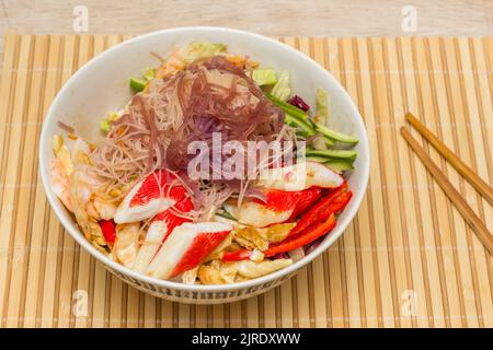 Salade asiatique de nouilles avec légumes et fruits de mer sur fond de bambou Banque D'Images