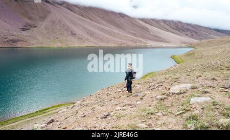 Mâle touriste se tenant au lac Chandra Taal surplombant l'eau du glacier bleu dans la vallée de Spiti Inde par jour nuageux Banque D'Images