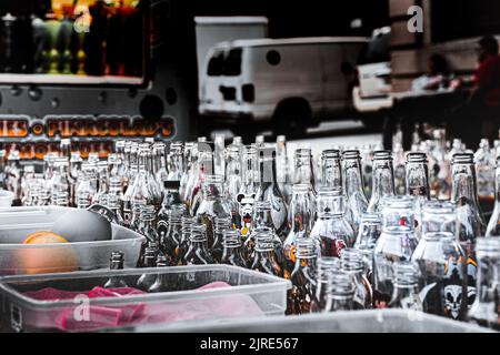 Les bouteilles de verre vides attendent d'être remplies d'art de sable coloré à la foire de 18th Avenue à Brooklyn Banque D'Images