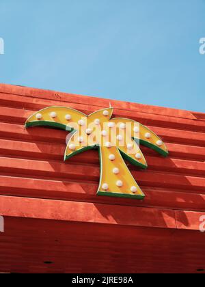 Un panneau jaune de palmiers lumineux sur les boutiques colorées cafés et l'architecture de bord de mer d'amusement de l'île de Canvey, l'estuaire de la Tamise, Essex, Angleterre Royaume-Uni Banque D'Images