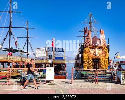 Un homme marche dans le port d'Alanya. Un immense navire avec une sculpture Viking à l'arrière du navire. Attraction touristique populaire. Banque D'Images