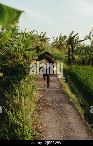 Jeune femme sportive faisant du yoga en plein air à Bali. Scorpion posture pose yoga, Vrischikasana. Un mode de vie sain Banque D'Images