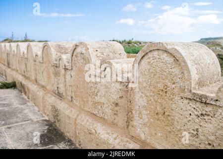 Une clôture en pierre calcaire ou une frontière décorée de petites et grandes arches en pierre autour de la chapelle Saint Dimitri dans le village rural de Gharb, Gozo, Malte Banque D'Images