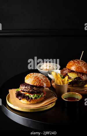 Deux savoureux cheeseburger et pommes de terre frites sur table sombre Copy space Banque D'Images