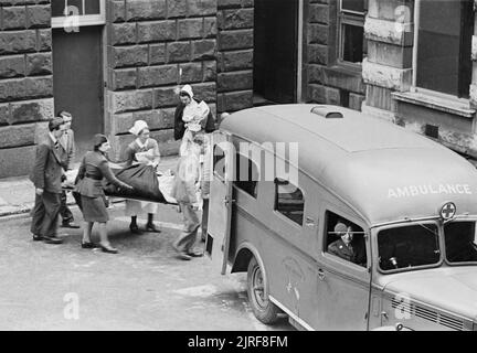 Guy's Hospital- La vie dans un hôpital de Londres, Angleterre, 1941 Un blessé est transporté sur une civière à une ambulance au Guy's Hospital de Londres. L'ambulance "a été présenté à l'Ambulance américaine Grande-bretagne par Fred un pauvre de Chicago, USA, juin 1940". La conductrice de l'American Ambulance ambulance Grande-bretagne peut être vu dans la cabine du véhicule. Banque D'Images