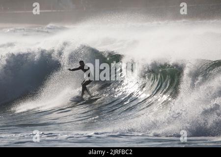 Un homme mince surfant sur les vagues mousseuse et haute barbotage dans la mer Banque D'Images