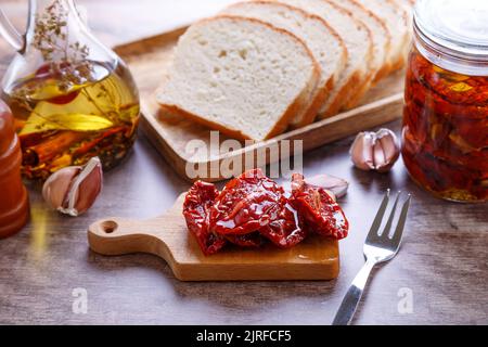 Tomates séchées à l'huile d'olive sur une mini-pension avec du pain maison dans un style rustique. Cuisine traditionnelle maison. Mise au point sélective, gros plan. Banque D'Images