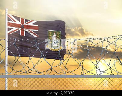 Mât avec le drapeau des îles Vierges britanniques contre le ciel et derrière une clôture avec fil barbelé. Le concept de la protection des frontières de territo Banque D'Images