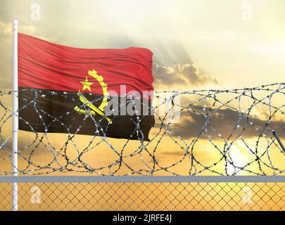 Mât avec le drapeau de l'Angola contre le ciel et derrière une clôture avec fil barbelé. Le concept de protection des frontières des territoires. Banque D'Images