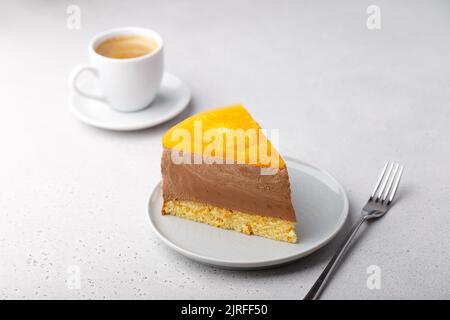 Gâteau à la mousse chocolat-orange avec base de biscuit, gelée et cercles d'orange. Un morceau de cheesecake maison et une tasse de café. Dessert traditionnel Banque D'Images