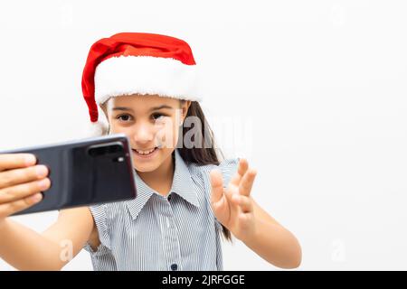 petite fille en chapeau de père noël avec smartphone sur fond blanc Banque D'Images