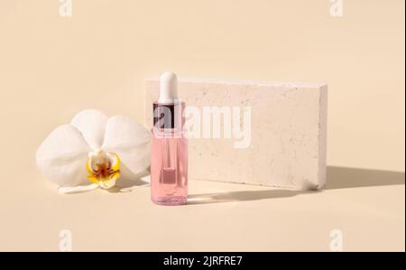 Flacon de Dropper rose clair avec sérum près de la fleur d'orchidée blanche sur jaune clair, gros plan, maquette. Produit de beauté pour le soin de la peau, huile aromatique ou sérum. Exoti Banque D'Images