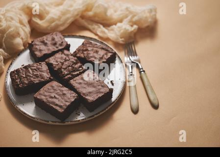 Brownies au chocolat maison servies sur une plaque blanche sur fond beige Banque D'Images