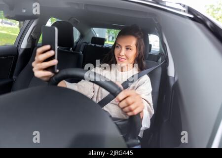 femme ou conducteur conduisant la voiture et prenant le selfie Banque D'Images