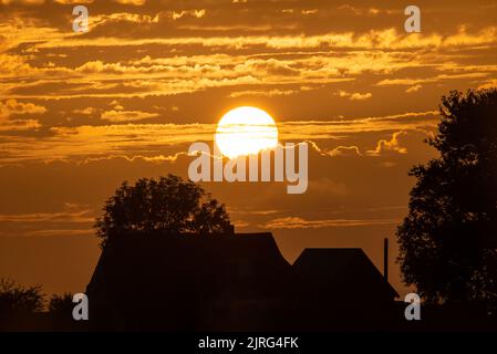 Coucher de soleil derrière les nuages au-dessus d'une maison Banque D'Images