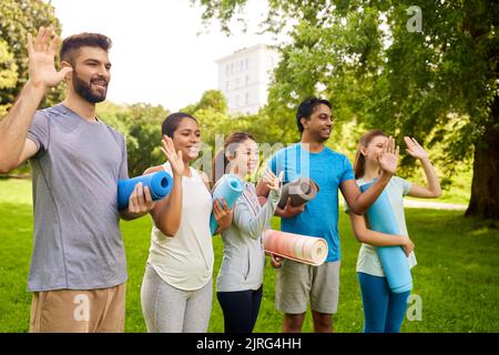 groupe de personnes heureuses avec tapis de yoga au parc Banque D'Images