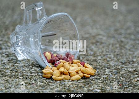 arachides salées grillées pelées dans un verre sur fond de béton. Banque D'Images