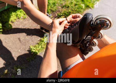 homme aidant la femme à mettre sur des rollerblades Banque D'Images