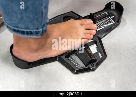 Femme mesure de la taille de chaussure dans le stockage. Dispositif déterminant la longueur pied Banque D'Images