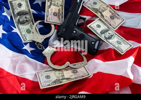 Menottes de police, dollars et une arme sur le drapeau des États-Unis, gros plan Banque D'Images