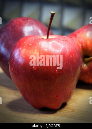 Une grande pomme rouge de la variété Red Chief, un gros plan. Gouttelettes d'eau sur la peau de la pomme. Fruits mûrs. Banque D'Images