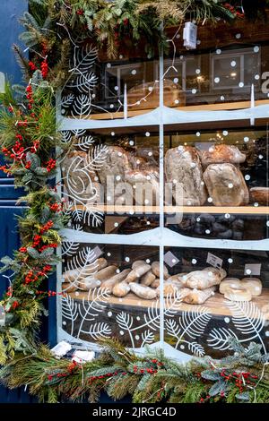 La fenêtre d'Une boulangerie est décorée avec Holly à l'heure de Noël, High Street, Lewes, East Sussex, Royaume-Uni. Banque D'Images