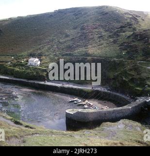 1971, historique, vue d'en haut du port à Boscastle, Cornouailles, Angleterre, Royaume-Uni, avec la marée dehors. Un endroit pittoresque sur la côte nord de Cornwall, le petit port a été construit à l'origine pour traiter le commerce de l'ardoise des carrières de Delabole voisines et avant la construction des chemins de fer, était un port prospère. Banque D'Images