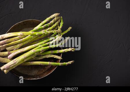 Tiges d'asperges crues. Arrière-plan sombre. Placer pour le texte. Banque D'Images