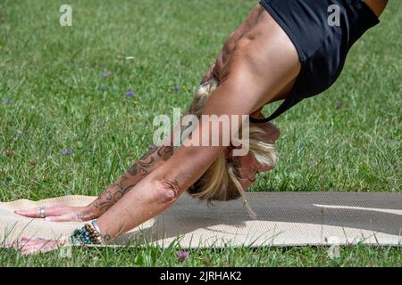 Partie du corps d'une femme européenne avec tatouages et perçage faisant du yoga Banque D'Images