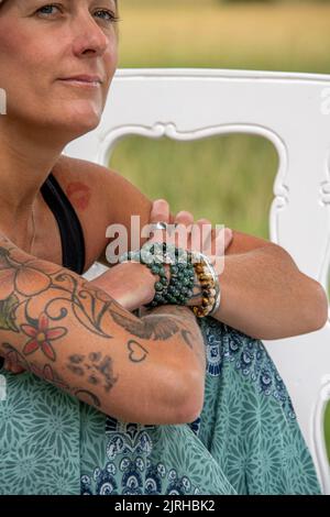 Partie du corps d'une femme européenne siting avec tatouages et piercing regardant loin Banque D'Images