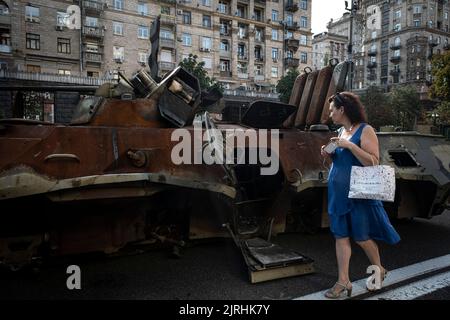 Kiev, Ukraine. 22nd août 2022. Une femme regarde un transporteur de personnel blindé russe (APC) détruit à Kiev. Consacrée à la prochaine Journée de l'indépendance de l'Ukraine, et près de 6 mois après l'invasion à grande échelle de l'Ukraine sur 24 février, la capitale du pays Kiev organise une exposition sur la rue principale de la rue Khreschaytk montrant plusieurs équipements militaires détruits, Chars et armes des forces armées de la Fédération de Russie (AFRF).alors que l'invasion russe complète de l'Ukraine a commencé sur le 24 février, la guerre qui a tué de nombreux civils et soldats, près de 9000 milles ukrainiens Banque D'Images