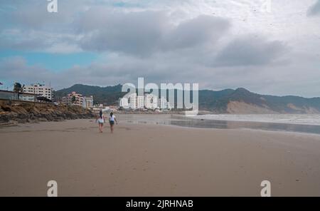 Bahia de Caraquez, Manabi / Equateur - 19 août 2022: Couple de femmes marchant sur la plage à côté de la promenade avec le centre-ville dans le backgroun Banque D'Images