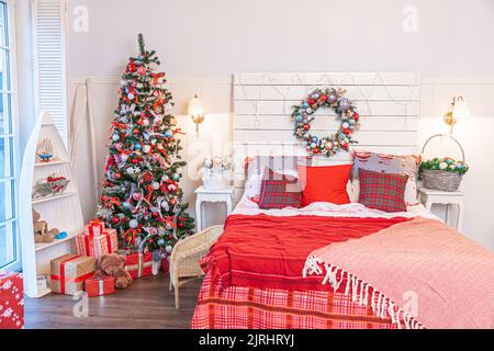 Cette chambre classique à l''intérieur comprend un sapin de Noël et des décorations traditionnelles rouges blanches.Chambre à coucher moderne de style classique, blanc et propre.La veille de Noël à la maison.Design minimaliste Banque D'Images