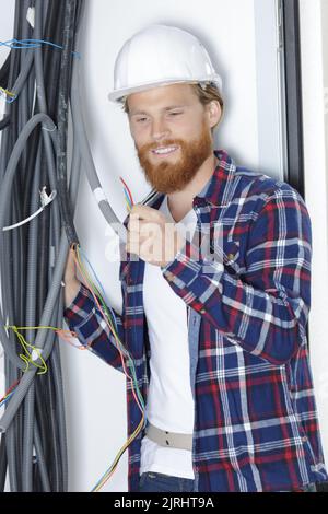 un électricien vérifiant les câbles électriques Banque D'Images