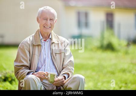 Dents blanches, sourire crasseux d'un homme âgé de 75 ans qui s'assoit dehors devant sa maison. Banque D'Images