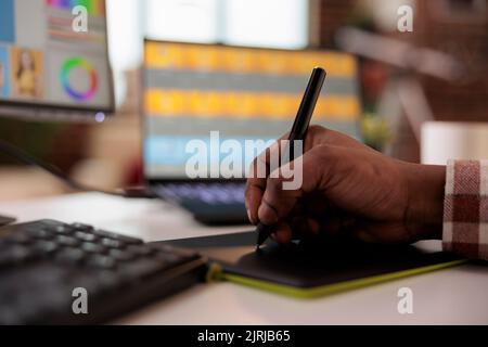Photographe masculin utilisant une tablette graphique et un stylet pour retoucher l'image, travaillant sur la production multimédia créative avec un logiciel de montage et une interface multimédia. Retouche de photos avec l'application. Gros plan. Banque D'Images