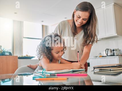 Famille faisant des devoirs dans le carnet, la mère aidant l'enfant avec le travail d'école à la maison et faisant le projet de classe pour l'éducation dans les livres. Écriture créative de fille Banque D'Images