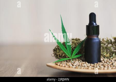 Huile de chanvre dans une bouteille en verre noir. Placer dans un plat avec des graines et des feuilles de cannabis. Concept de traitement. Thérapie de relaxation. Médecine alternative. Banque D'Images