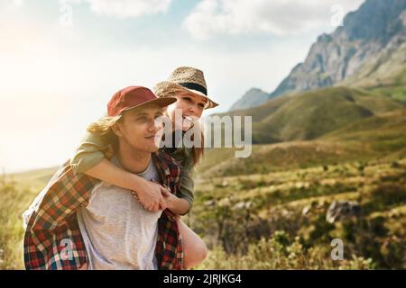 L'amour véritable est vraiment gratuit. Un jeune couple heureux qui profite d'une promenade en pigeyback dans la nature. Banque D'Images