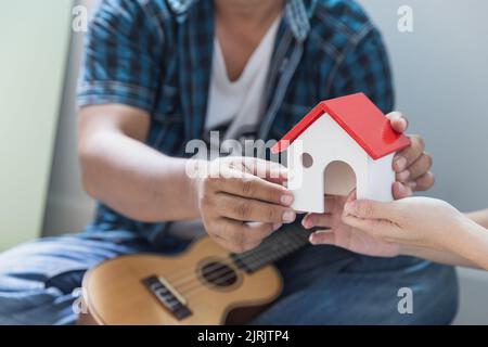 Couple tenant la maison modèle, nouvelle maison en main et achetant la nouvelle maison et se déplaçant ensemble des affaires et le concept immobilier. Banque D'Images
