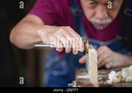 Un homme travaille dans une boutique de menuiserie. Menuisier travaillant sur les machines à travailler le bois dans l'atelier de menuiserie. Banque D'Images