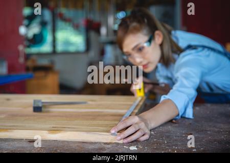 femme travaille dans une boutique de menuiserie. Menuisier travaillant sur les machines à travailler le bois dans l'atelier de menuiserie. Banque D'Images