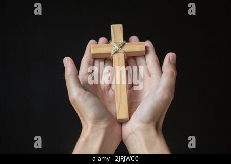 Les mains humaines tenant une croix sainte et priaient pour des bénédictions de Dieu, le concept de Dieu du culte d'Amour. - image Banque D'Images