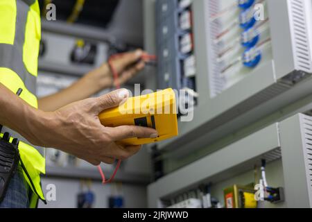 Testeur de travail électricien mesurant la tension et le courant de la ligne électrique d'alimentation dans le contrôle d'armoire électrique. Banque D'Images